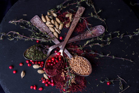 Herbs and spices selection in old metal spoons on a black background