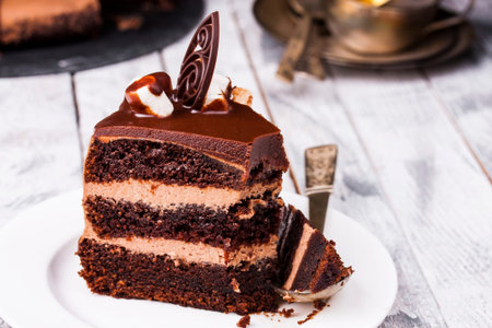 Delicious dark chocolate cake in white plate on wooden table background