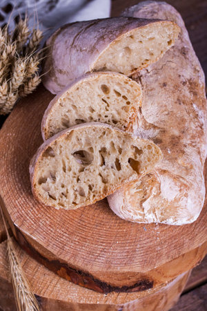 Homemade ciabatta with ears of wheat on a wooden table