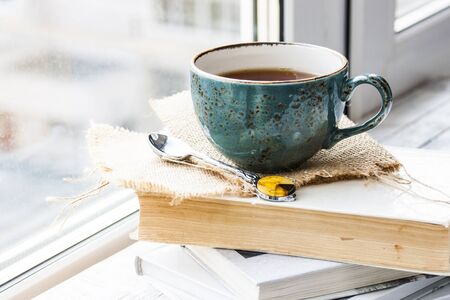 tea cup on the window sill and bookの写真素材