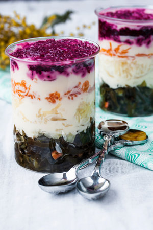 layered salad with sea cabbage, beets, potatoes and carrots in a glass