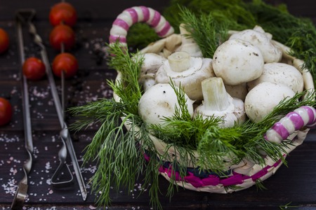 fresh mushrooms with dill and tomatoes on dark wooden backgroundの写真素材