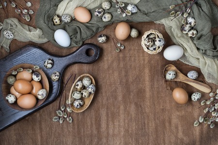 Easter eggs in chicken and quail with willow twigs on wooden background, top viewの写真素材
