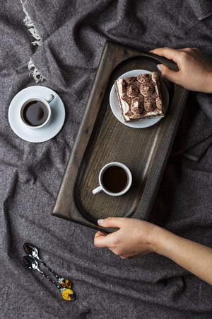 Breakfast with strong coffee and tiramisu cake on wooden trayの写真素材