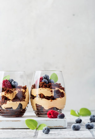 Chocolate biscuit dessert in glasses with raspberries and blueberriesの写真素材