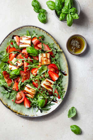 salad with strawberries, tomatoes, arugula and halloumi cheeseの写真素材