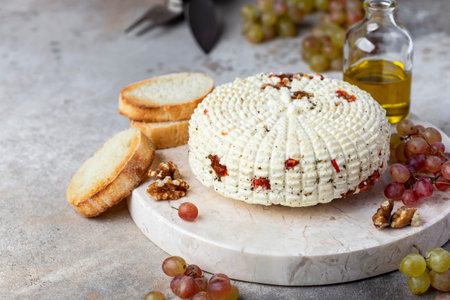 round homemade cheese with herbs and dried tomatoesの写真素材