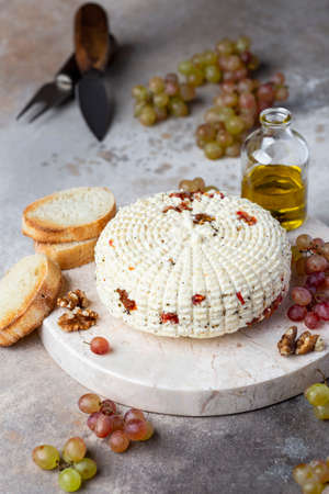 round homemade cheese with herbs and dried tomatoesの写真素材