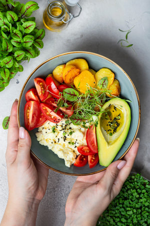 Scrambled eggs with cherry tomatoes, avocado, fried potatoes and micro-greens