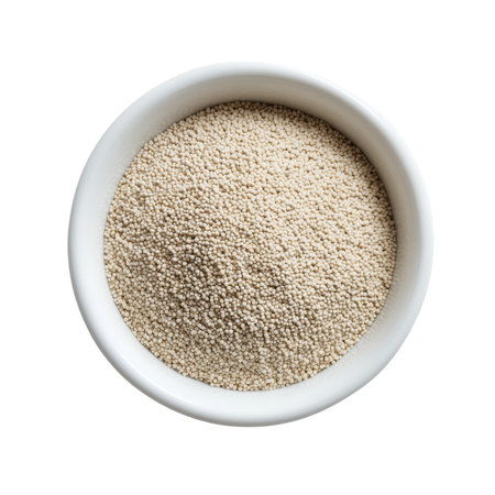 A white bowl is filled with a mound of small, light beige amaranth grains. The tiny, round seeds are densely packed and viewed from a top-down perspective. The texture of the grains is finely detailed, and the image is set against a plain black background, highlighting the amaranth.の素材