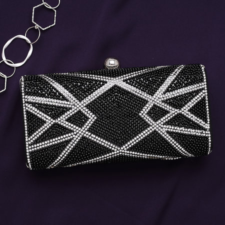 Black and silver women's clutch with a jewelry on a dark purple background top view.の写真素材