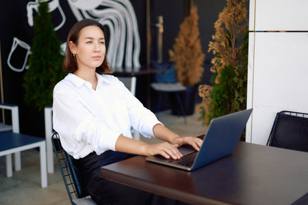 Portrait of a business woman with a laptop near the office, concept of a strong and independent woman.の写真素材