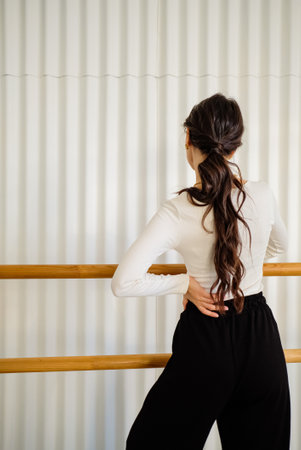 Beautiful young girl in black trousers with a white ru on a background of a white ribbed wall. Casual look. Life styleの写真素材