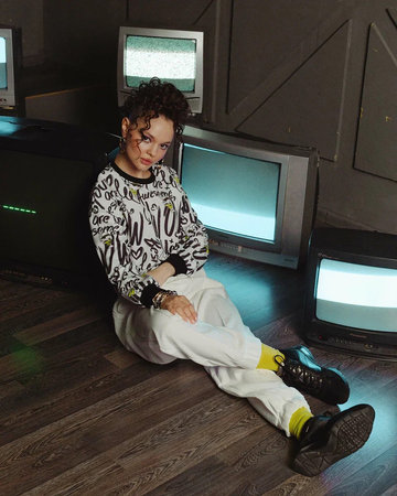 young woman with smokes and designer clothes. next to an old retro TV. Casual style