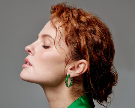 A cheerful model beautifully adorned in a vibrant green satin outfit is showcasing grace and eleganceの写真素材