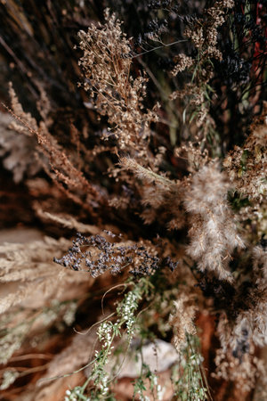 An arrangement of textured grasses and plants in natural, earthy hues creates a rustic and calming...