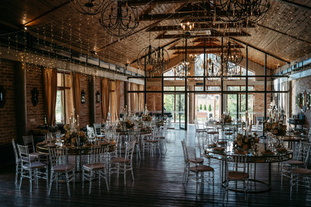 This elegant rustic wedding venue features round tables adorned with floral centerpieces and chandeliers, offering a cozy and sophisticated ambiance for memorable events.の写真素材