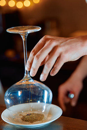 Hand gently lifts an upside-down wine glass over a plate of spices, capturing the essence of elegant...