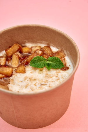 A warm, creamy oatmeal topped with cinnamon-spiced apples and a fresh mint garnish, served in an...