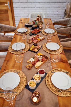 A stylish table setting with an elegant charcuterie spread, empty plates, and wine glasses, ready...