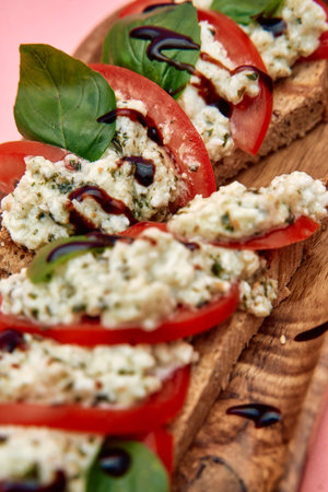 A freshly prepared bruschetta featuring creamy ricotta, juicy tomatoes, basil leaves, and balsamic...