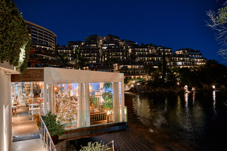 A luxurious coastal resort illuminated at night, with a beautifully lit restaurant by the waterfront, exuding elegance and offering a stunning view for a perfect getaway.の写真素材