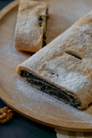 Deliciously Prepared Strudel with Poppy Seed Filling Generously Dusted with Powdered Sugar on a Wooden Board Perfectly Displayed for Tempting Dessertの写真素材