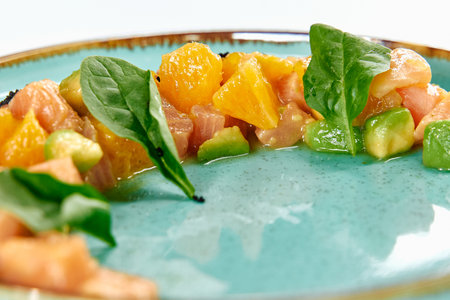 A Vibrant Medley of Fresh Salmon, Citrus, and Greens Artfully Presented on a Turquoise Plate for a Delightful Culinary Experienceの写真素材
