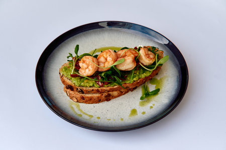Deliciously Crafted Avocado Toast Topped with Succulent Shrimp and Fresh Microgreens, Artfully Presented on a Modern Plateの写真素材