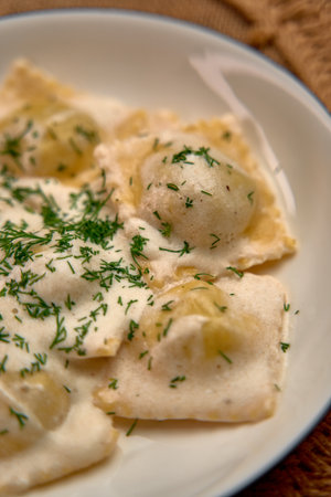 Delicious Homemade Ravioli with Creamy Sauce and Fresh Herbs Served in a White Bowl for a Perfect Culinary Experienceの写真素材