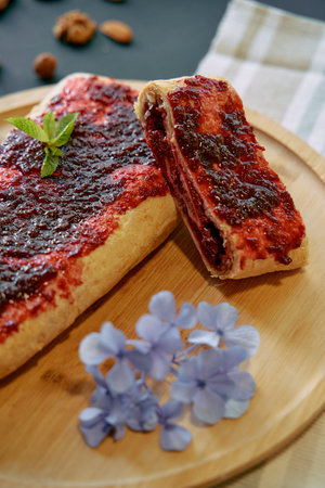 Delicious Homemade Berry Jam Pastry with a Flaky Crust and Garnished with Fresh Mint and Edible Flowers on a Wooden Plateの写真素材
