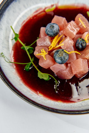 Deliciously Fresh and Colorful Dish Featuring Cubes of Raw Fish, Blueberries, and a Sweet Berry Sauce, Garnished with Fresh Herbs and Zest for a Burst of Flavorの写真素材