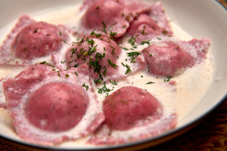 Deliciously Crafted Pink Ravioli Served in Creamy Sauce Garnished with Fresh Herbs for a Flavorful Culinary Experienceの写真素材