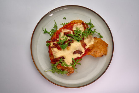 Deliciously Baked Chicken Dish Topped with Mozzarella, Bacon, and Fresh Arugula, Perfectly Layered for a Mouthwatering Meal Experienceの写真素材