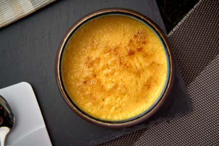 Deliciously Caramelized Dessert with Smooth, Creamy Texture Served in a Dark Ceramic Bowl on a...