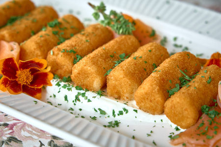 A Delicious Platter of Golden-Brown Croquettes Garnished with Fresh Herbs and Colorful Edible...