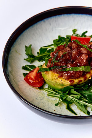 A Vibrant Dish Featuring Fresh Avocado and Hearty Toppings on a Bed of Greens, Garnished with Cherry Tomatoes for a Wholesome Culinary Delightの写真素材