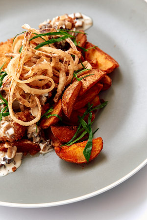 Crispy Fried Potatoes Topped with Delicious Onions and Fresh Herbs Served on a Stylish Plate