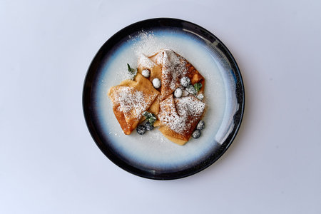 Delicious Platter of Fluffy Crepes Topped with Fresh Berries and a Light Dusting of Powdered Sugar...