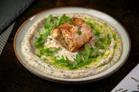 Deliciously Presented Roasted Meat Roll on a Creamy Mashed Base with Fresh Greens and Herb Drizzle...