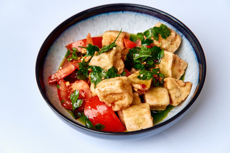 A vibrant dish featuring crispy tofu cubes mingled with ripe tomatoes, fresh herbs, and spices, creating a delightful vegetarian plate full of flavor.の写真素材