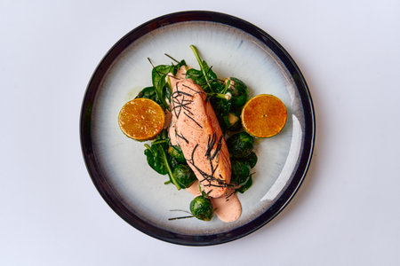 A Deliciously Plated Salmon Fillet with Spinach and Citrus Garnish, Showcasing Culinary Artistry and Fresh Ingredients in Every Biteの写真素材