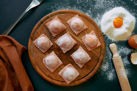 A Delicious Display of Homemade Ravioli on a Wooden Board Surrounded by Flour, Eggs, and Kitchen Utensils for Culinary Inspirationの写真素材