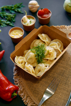 Delicious Dumplings Served in a Box Accompanied by Fresh Ingredients and Dipping Sauces for a Flavorful Culinary Experienceの写真素材