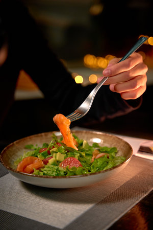 A Close-Up of a Delicious Salad with Fresh Ingredients Being Enjoyed with a Fork in a Cozy Dining Setting That Evokes Warmth and Flavorful Experiencesの写真素材