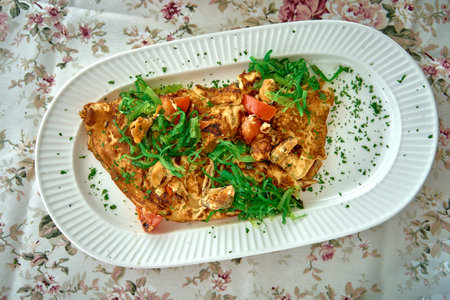 A Deliciously Prepared Omelette Garnished with Fresh Vegetables on a Decorative Plate Surrounded by...