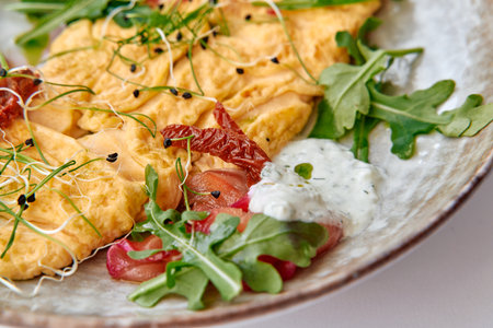 Delicious Gourmet Omelette Served with Fresh Greens, Sprouts, and Zesty Sauce on a Stylish Plate, Perfect for a Nutritious Breakfast Experienceの写真素材