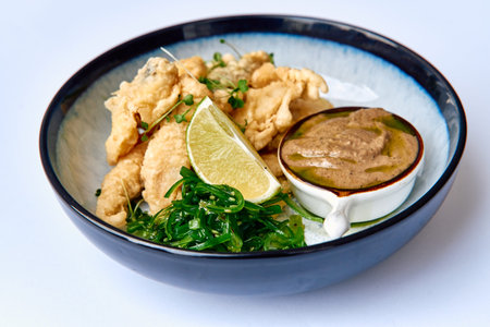 Deliciously Crispy Fried Fish Served with Fresh Lime, Seaweed Salad, and a Rich Dipping Sauce for an...