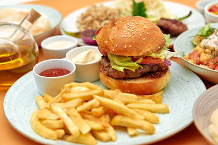 A Delicious Plate Featuring a Juicy Hamburger with Fresh Vegetables, accompanied by Crispy French...