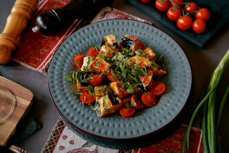 Deliciously Plated Dish Featuring Grilled Eggplant, Fresh Cherry Tomatoes, and Chopped Herbs for a...